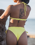 Woman wearing the Buttercup Top in yellow, a triangle bikini with push-up padding, adjustable straps, and rose gold hardware, showcasing a flattering fit.