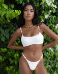 Woman wearing the Daisy Top in white, showcasing its supportive push-up design with adjustable straps and rose gold trimming.