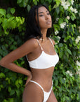 Woman wearing the Daisy Top in white, showcasing its push-up padding and adjustable straps for support and lift.
