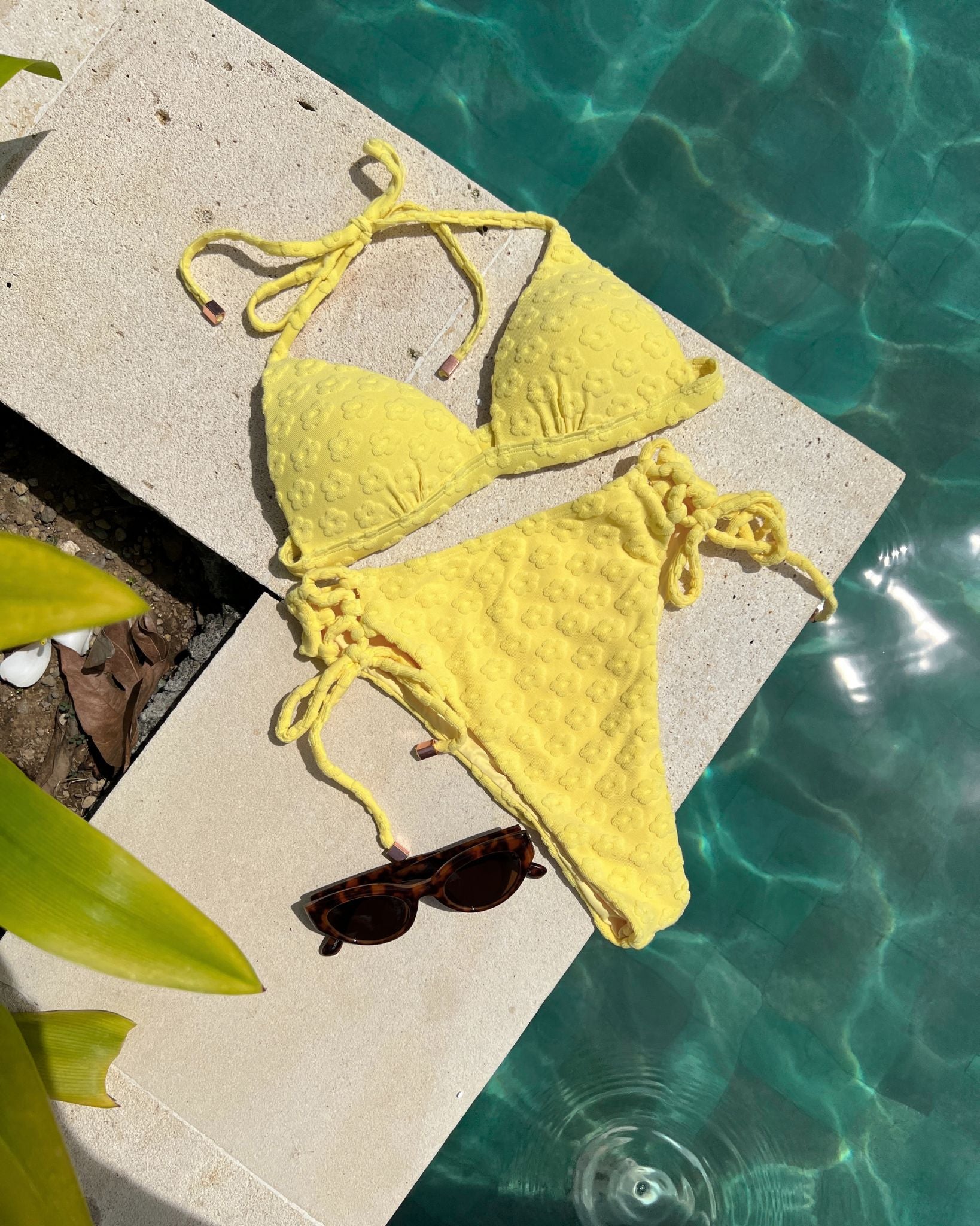 Azalea Bottom / Yellow lace-up bikini bottom on pool ledge with sunglasses, featuring high waist, high leg cut, and rose gold hardware.