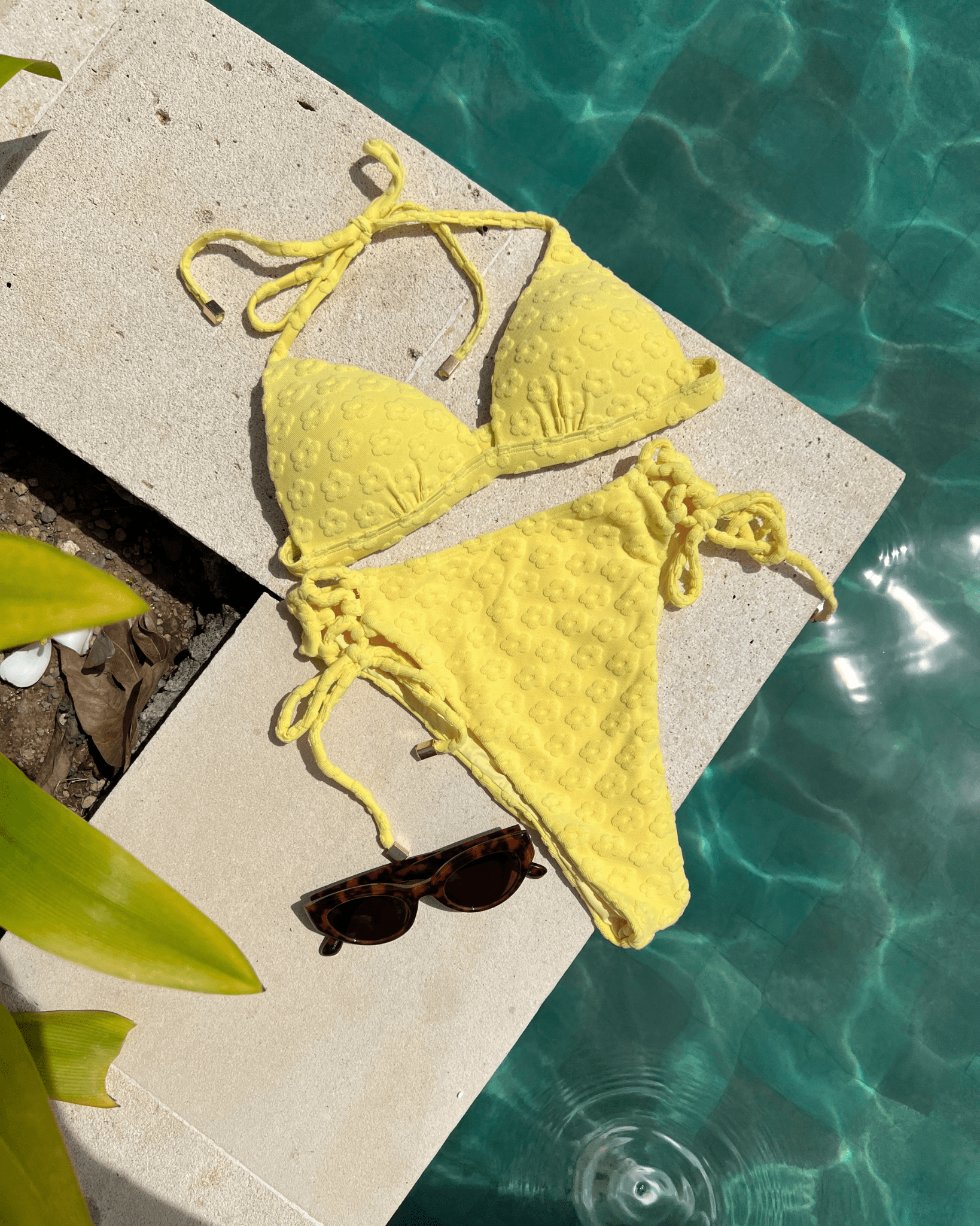 Buttercup Top / Yellow bikini and sunglasses on stone ledge by pool.